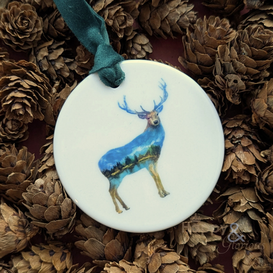 Decorative ornament with a blue deer design on a white background, surrounded by pine cones.