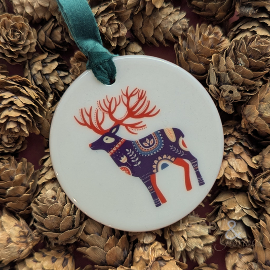 Decorative ornament with a reindeer design on a bed of pine cones